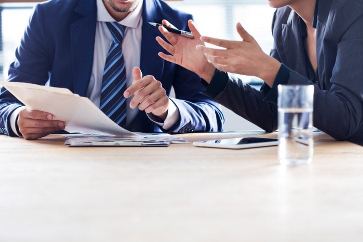 business-people-discussion-working-concept Business conversation about documents between man and women both in suits. Faces not visible.