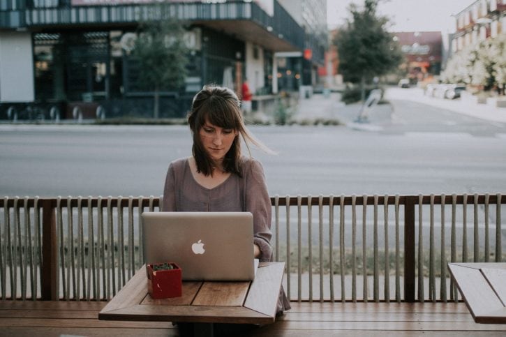 woman_in_gray_shirt_sitting_on_bench_in_front_of_MacBook woman in gray shirt sitting on bench in front of MacBook